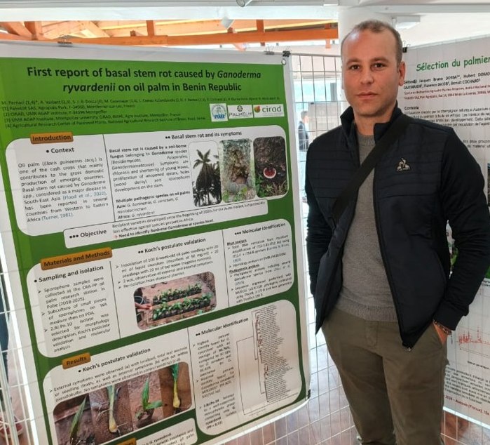 Dr Pernaci Michael devant son poster au congrès de phytopathologie à Aussois en France. Le poster est intitulé "First report of basal stem rot caused by Ganoderma ryvardeni on oil palm in Benin Republic"